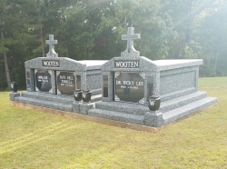 Side-by-side deluxe and single deluxe deep gray with cross, granite inlays in the columns, vases and pedestals, step-up trim pieces on a cement foundation in Vina, AL